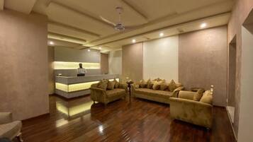 A spacious room with a reception desk, a sofa set, and a ceiling fan.