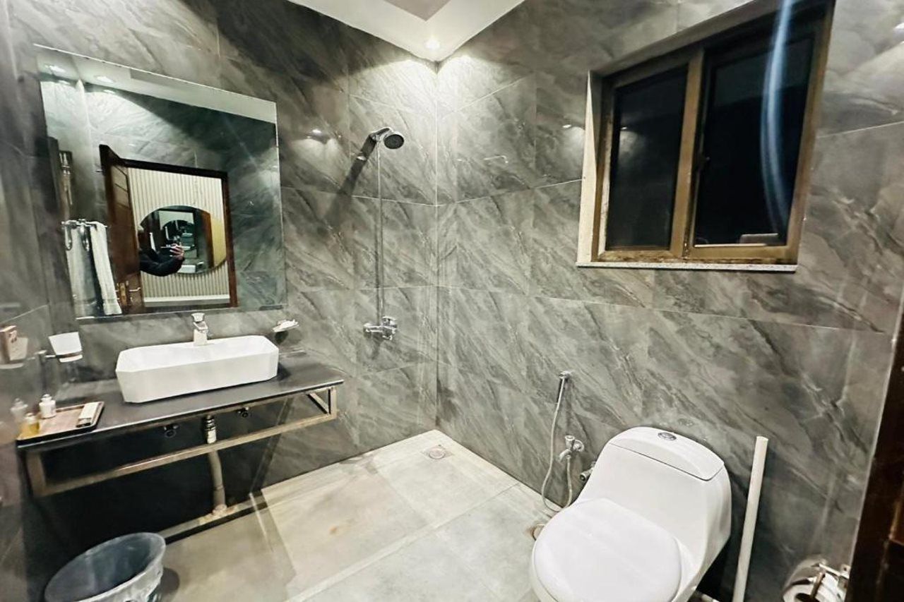 A bathroom with a white sink, a mirror, a shower, and a toilet.