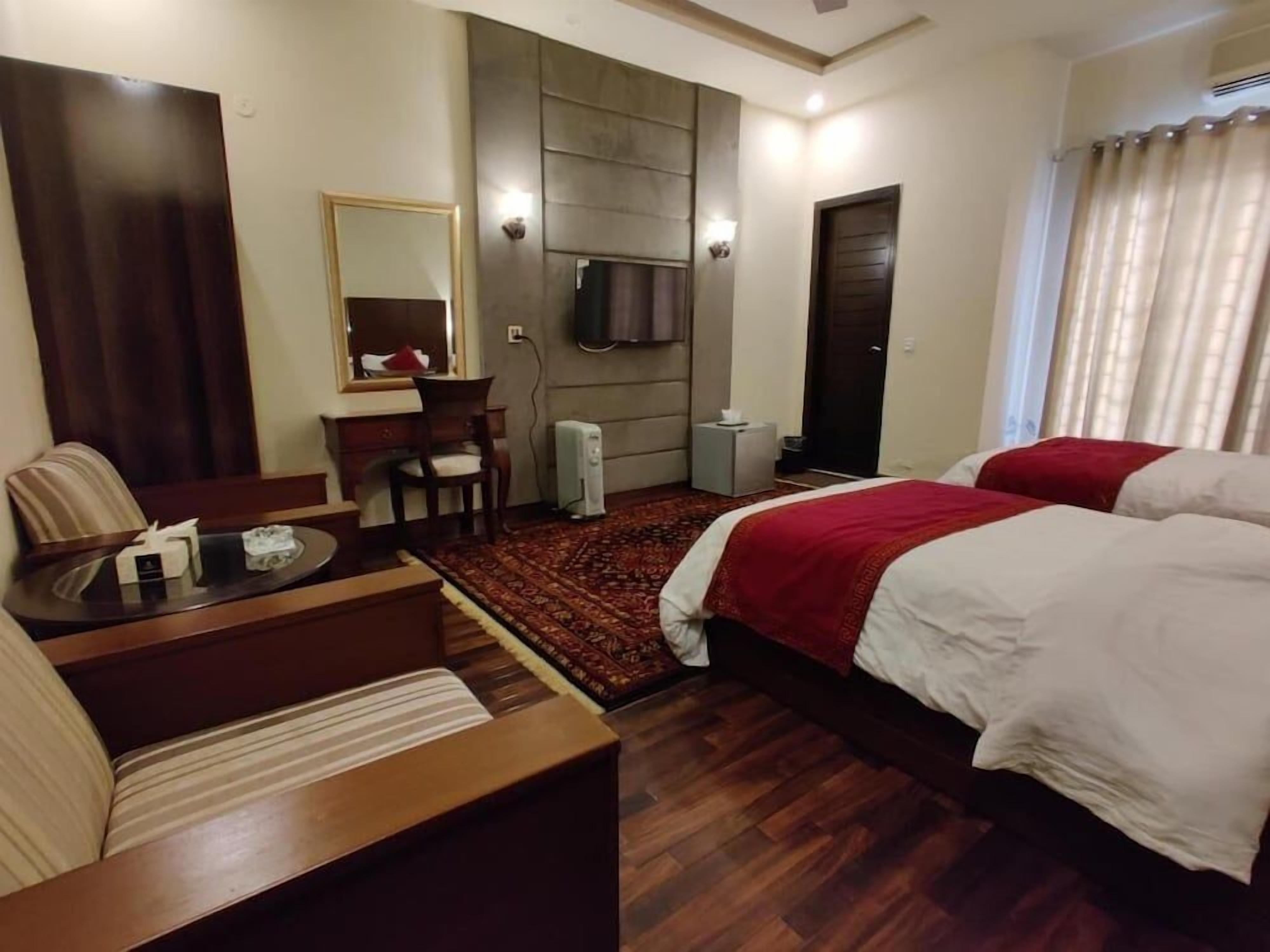 Une chambre d’hôtel équipée d’un lit, d’un bureau, d’une chaise, d’une télévision et d’un grand miroir.