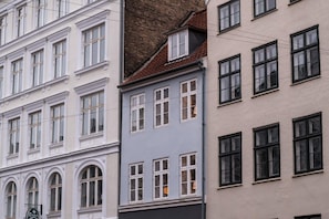 En række høje bygninger i forskellige arkitektoniske stilarter, herunder en bygning med teglhængt tag og en anden med flad facade.