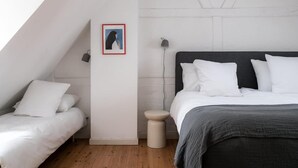 Ein Schlafzimmer mit einem Bett, einem Nachttisch, einer Lampe und einem gerahmten Bild an der Wand.