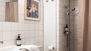 Ein Badezimmer mit Dusche, Toilette, Waschbecken und einem gerahmten Bild an der Wand.