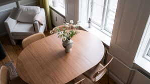 Ein Zimmer mit einem runden Holztisch, einer Couch und einem Fenster mit Vorhängen.