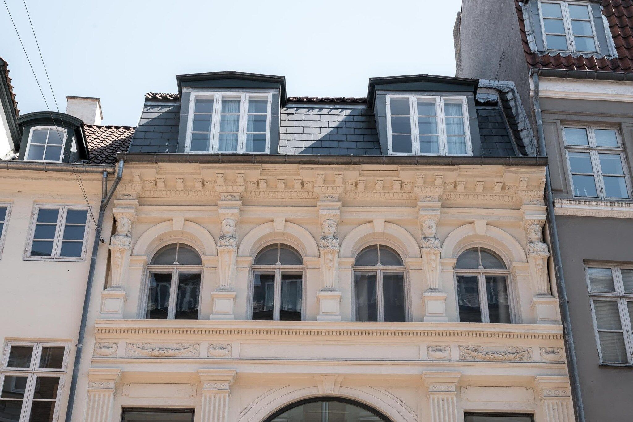 En bygning i klassisk arkitektonisk stil, med et markant buet vindue og en dekorativ gesims over vinduet.