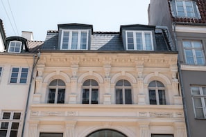 En bygning i klassisk arkitektonisk stil, med et markant buet vindue og en dekorativ gesims over vinduet.