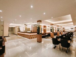 Vestíbulo de hotel con recepción, zona de estar y suelo pulido.