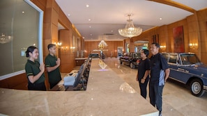 A hotel lobby with a reception desk, a chandelier, and a classic car. - Hotel Puri Senyiur (Samarinda)