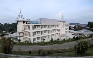 A multi-story building with a symmetrical facade, featuring a central clock tower and two smaller towers on either side. - Hotel Puri Senyiur (Samarinda)