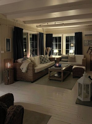 Ein gemütliches Wohnzimmer mit Korbmöbeln, einem Couchtisch und einer weißen Stehlampe.