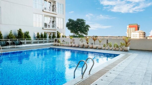 Une piscine avec vue sur un bâtiment et un arbre en arrière-plan.