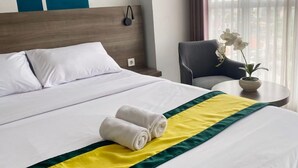 Une chambre d’hôtel avec un lit, une chaise et une petite table sur laquelle est posée une plante.