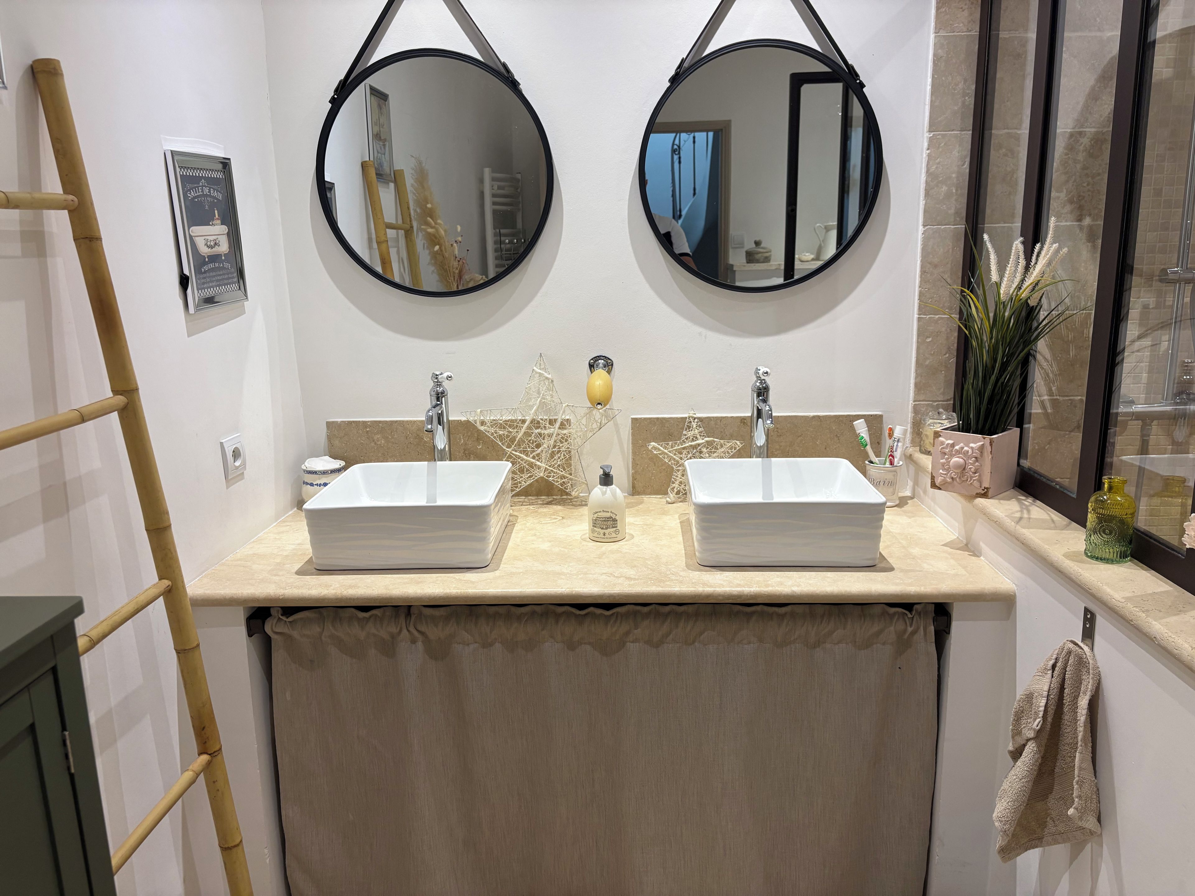 Un bagno con due lavandini, uno specchio sopra ciascuno e un asciugamano appeso al muro.