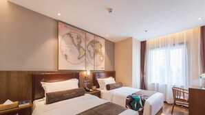A hotel room with two beds, a large world map on the wall, a desk, and a chair. - James Joyce Coffetel (Beijing)