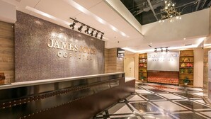 A reception area with a modern design, featuring a reception desk, a wall with a mosaic pattern, and a chandelier. - James Joyce Coffetel (Beijing)