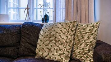 A sectional sofa with patterned cushions in a room with a window and a vase on a side table.