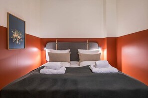 Hotellihuone, jossa on sänky, tyynyjä ja seinällä kehystetty taulu.