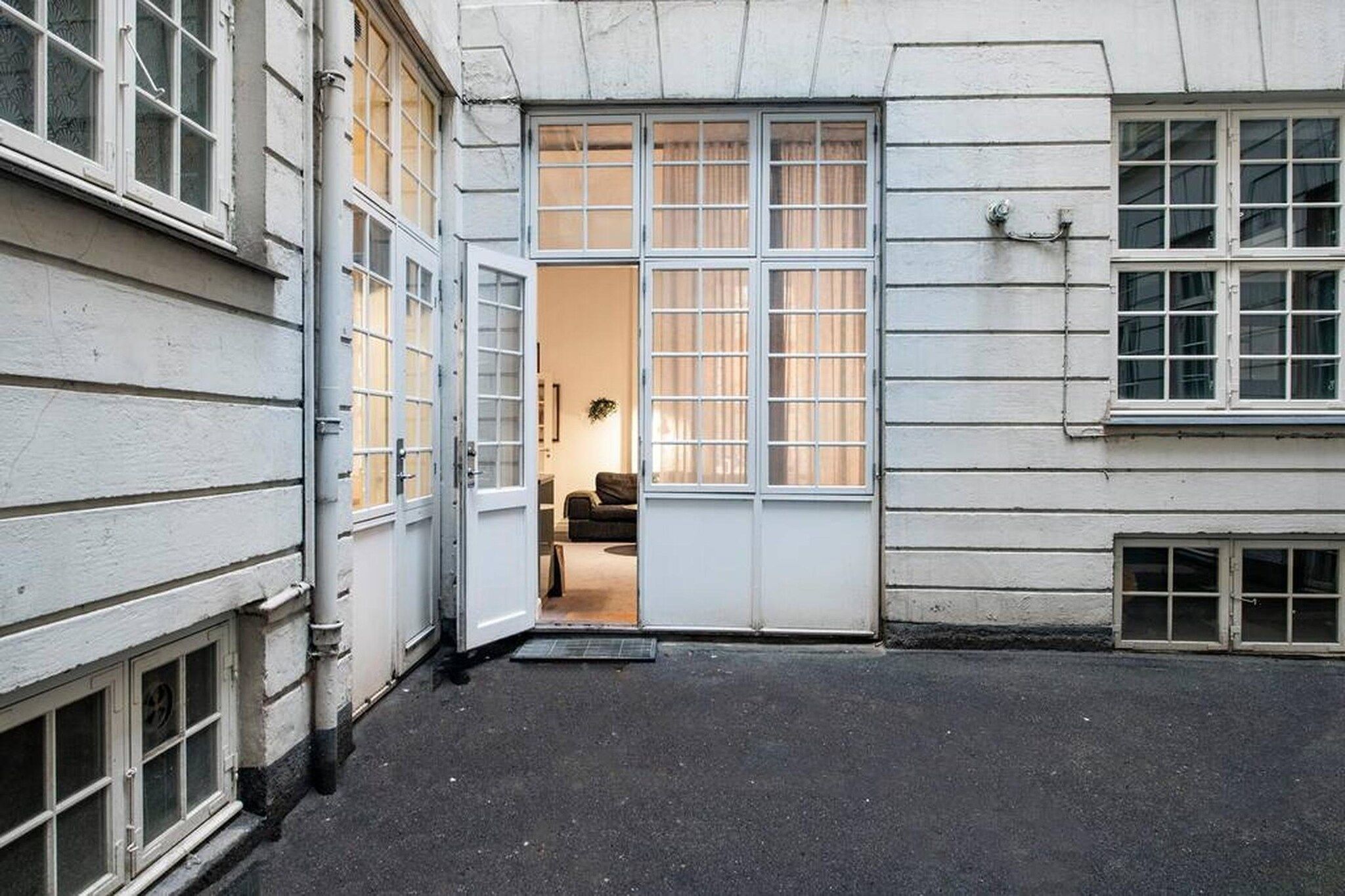 A building with a courtyard, a door leading to an interior space, and a window with curtains.