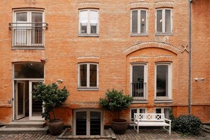 A building with multiple windows, a door, and two potted plants. - Apartment with Courtyard Access (København)