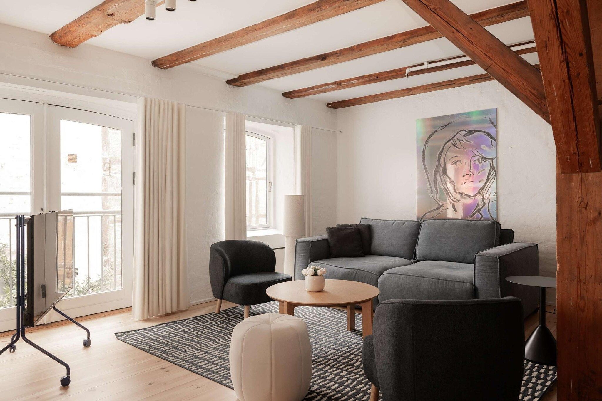 A modern living room with a grey sofa, a black armchair, a round coffee table, and a patterned rug.