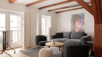 A modern living room with a grey sofa, a black armchair, a round coffee table, and a patterned rug.