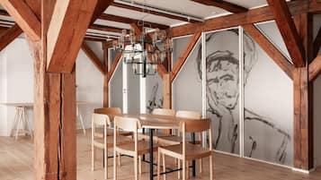 Un comedor con vigas de madera, una araña y un cuadro abstracto grande en la pared.