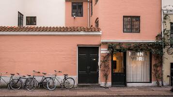 A building with a closed black door, a row of bicycles parked outside, and a shop with a sign reading 'NINNA YOORK'.