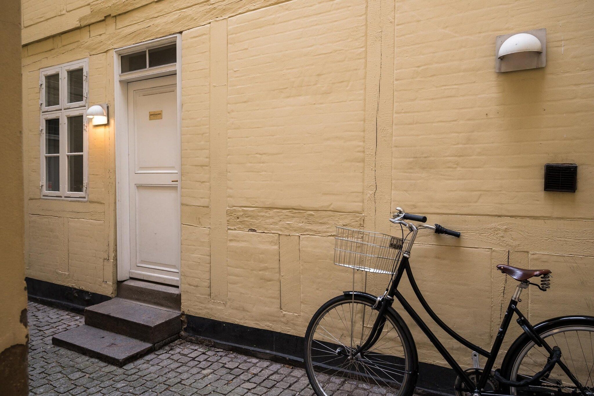 Ein Fahrrad, das an einer Wand geparkt ist und einen Korb vorne trägt.