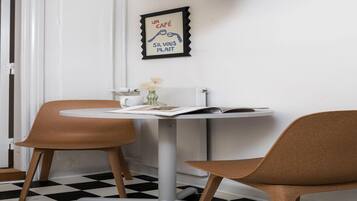 A dining area with a round table, two chairs, a framed picture on the wall, and a checkered floor.