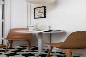 A dining area with a round table, two chairs, a framed picture on the wall, and a checkered floor. - Chic Stay by City Square (København)