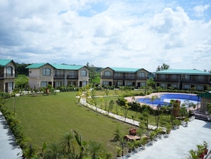 Hotel com vários edifícios, piscina e jardins bem cuidados.