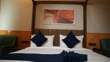 A hotel room with a bed, two pillows, a blanket, and a painting on the wall.
