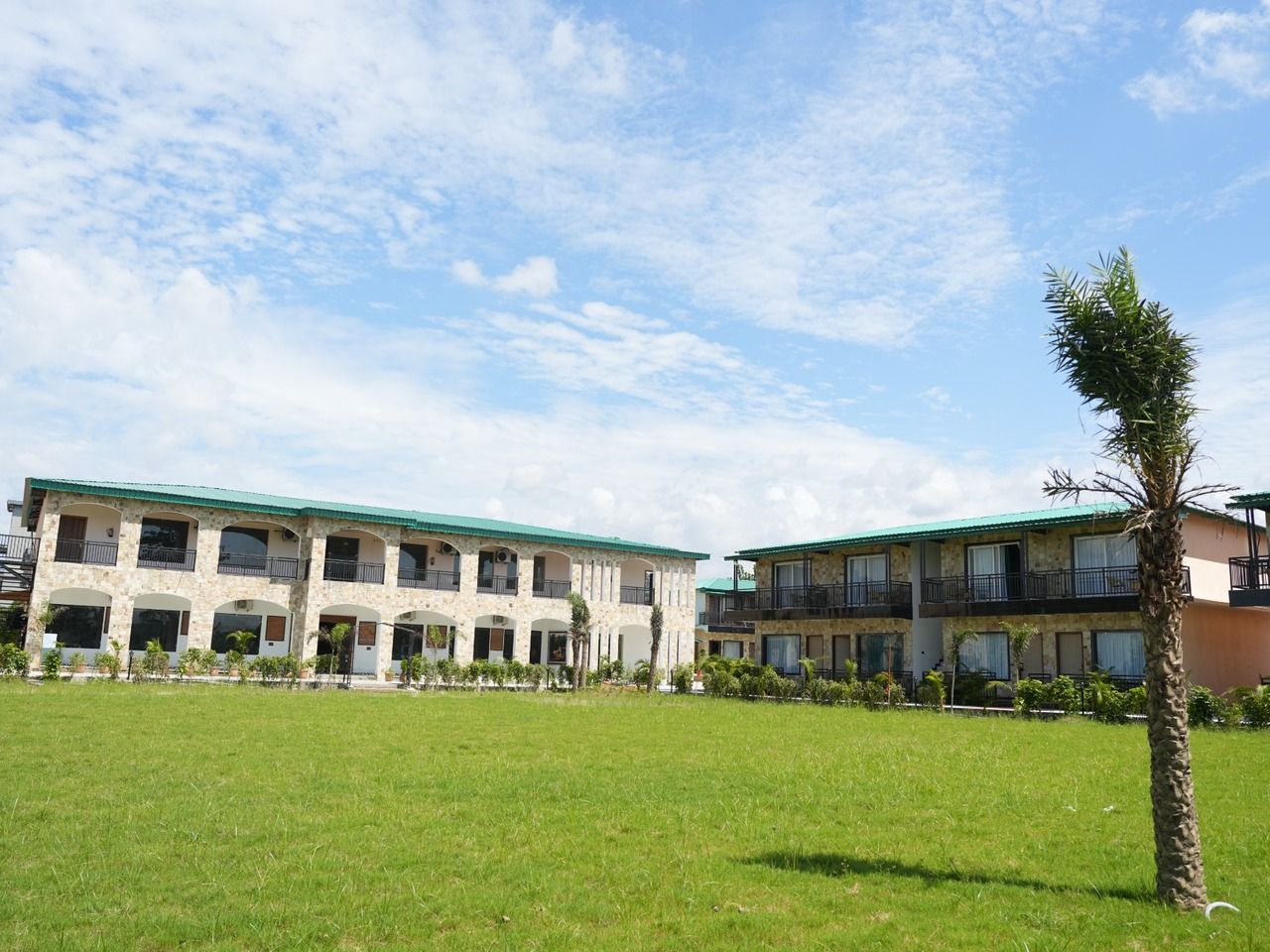A building with multiple balconies and a green lawn in front.
