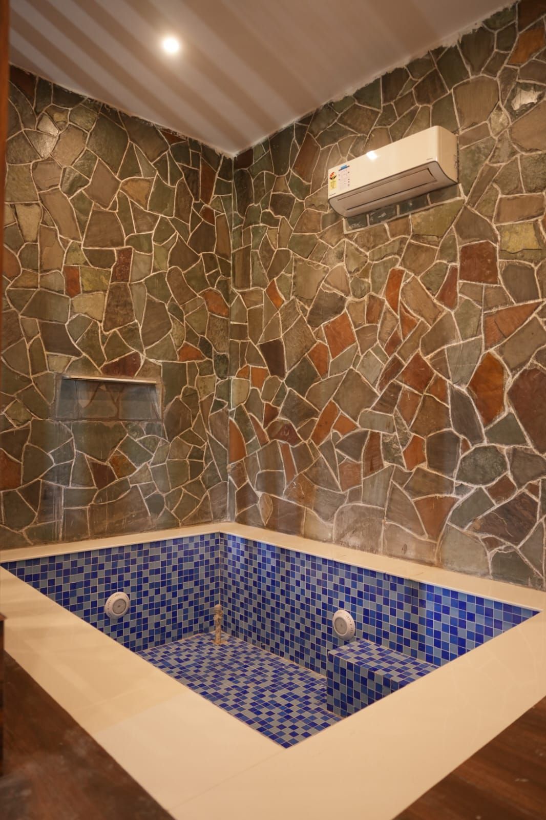 Een badkamer met stenen muren en een blauw betegeld bad.