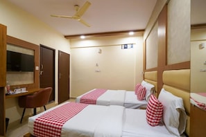 Habitació d'hotel amb dos llits, escriptori, cadira, televisió i ventilador de sostre.
