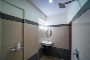A small bathroom with a sink, mirror, and shower. - HILVON BUSINESS HOTEL (Bengaluru)