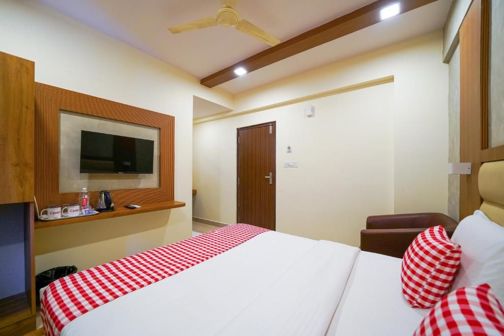 Quarto de hotel com cama, televisão na parede, ventilador de teto e armário de madeira.