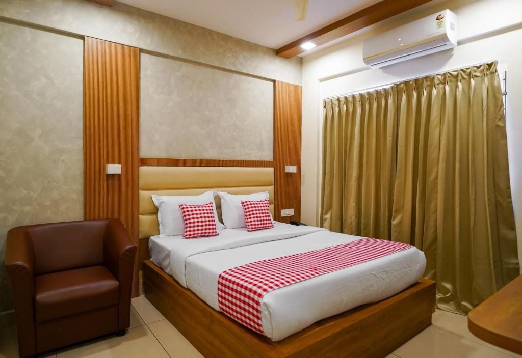 Camera d'albergo con un letto, una sedia, una testiera in legno, un condizionatore d'aria e una tenda.