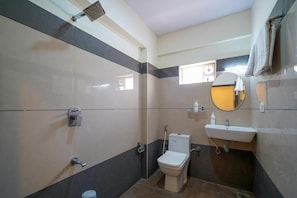 A bathroom with a toilet, sink, mirror, and shower. - HILVON BUSINESS HOTEL (Bengaluru)
