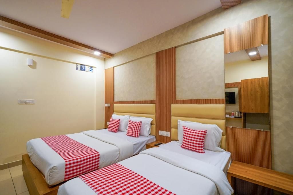 A hotel room with two beds, a wooden headboard, a mirror, and a small bedside table.