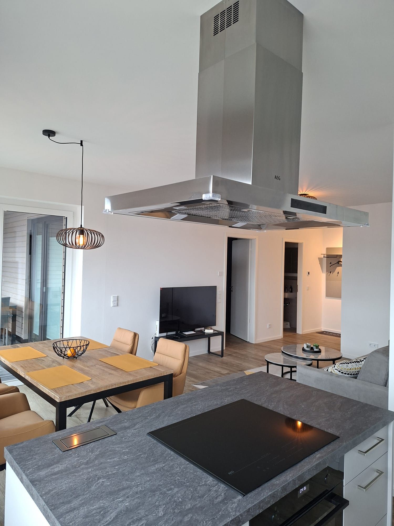 A modern kitchen with a built-in stove, a dining area with a table and chairs, and a living area with a TV.