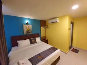 A hotel room with a bed, a nightstand, a wall-mounted air conditioner, and a door. - Enrich Hotel Puncak Alam (Ijok)