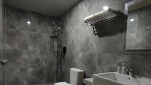 Une salle de bain moderne équipée d’une douche, de toilettes, d’un lavabo et d’un miroir.