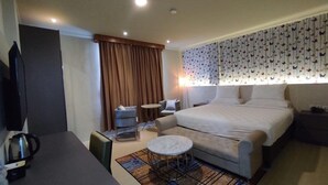 Une chambre d’hôtel comprenant un lit, un bureau, une chaise, une petite table ronde et un téléviseur.