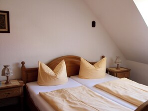 A bedroom with a wooden headboard, two bedside tables, a lamp, and a framed picture on the wall. - Reutemann Guesthouse WG1 - Cozy vacation rental in a quiet, central location (Nonnenhorn)