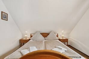 A bedroom with a single bed, two bedside tables, and a wooden headboard. - Reutemann Guesthouse WG2 - Cozy vacation rental in a quiet, central location (Nonnenhorn)