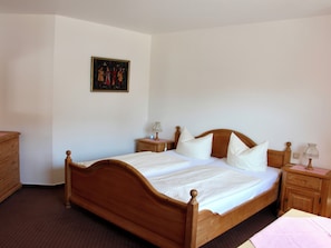 A neatly made double bed with a wooden headboard, two bedside tables with lamps, a wooden dresser, and a framed picture on the wall. - Reutemann Guesthouse WG3 - Cozy Vacation Rental with a Terrace (Nonnenhorn)