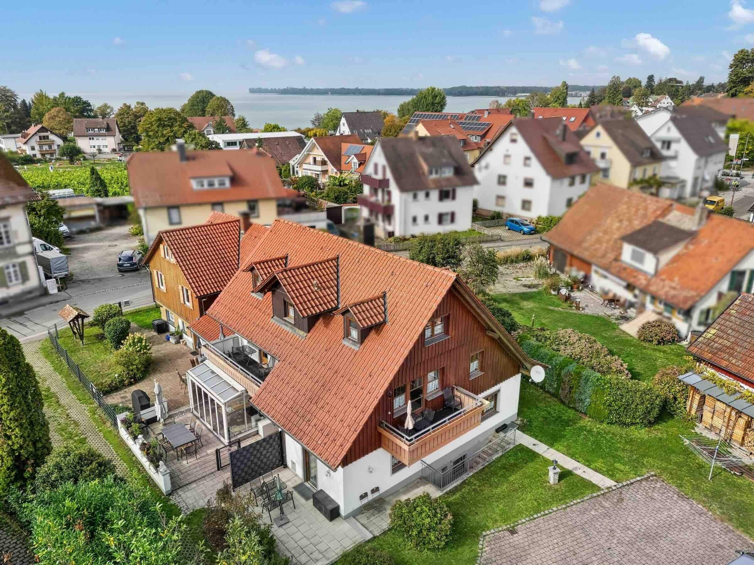 Un quartier résidentiel avec des maisons, un ciel dégagé et une étendue d’eau visible au loin.