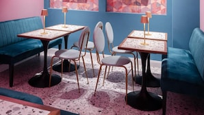 A room with teal sofas, a coffee table, and chairs. There are two framed pictures on the wall.