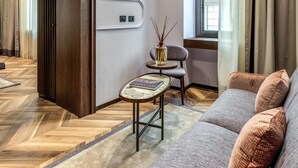 Un salon moderne avec un canapé, une petite table et une fenêtre avec des rideaux.