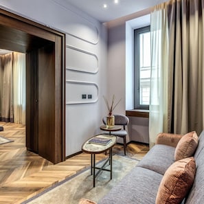 A modern living room with a sofa, a small table, and a window with curtains. - THE Steps Hotel by Eitch Collection (Rome)